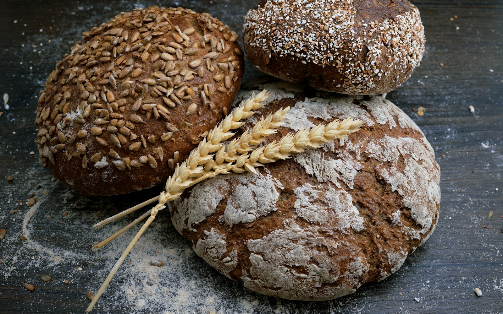A baker's hands placing a freshly scored sourdough loaf into the oven